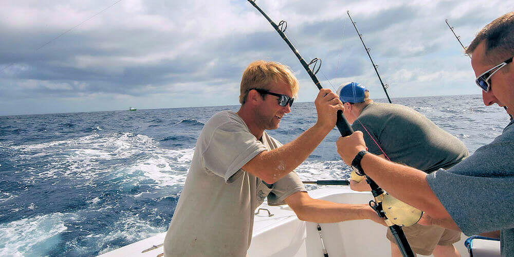 Longer Days Fishing Charter's mate helping client fight big yellowfin tuna on offshore charter at Cape Hatteras.